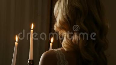 在黑暗的房间里，一头卷曲的头发拿着烛<strong>台</strong>和闪电蜡烛的金发女郎的特写后景。